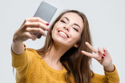 Smiling woman taking selfie after teeth straightening treatment