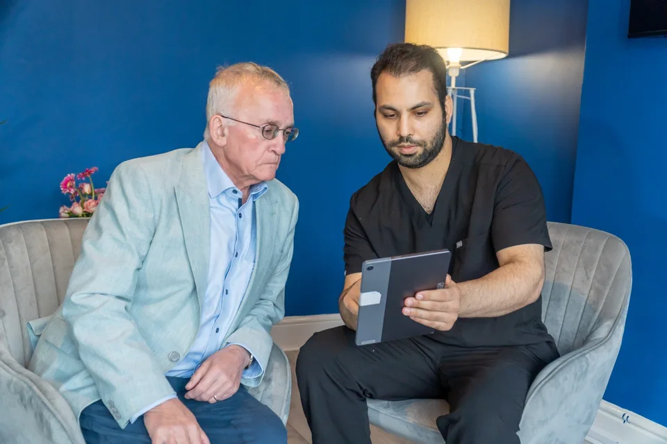Dentist consulting older patient about dental implants using a digital tablet