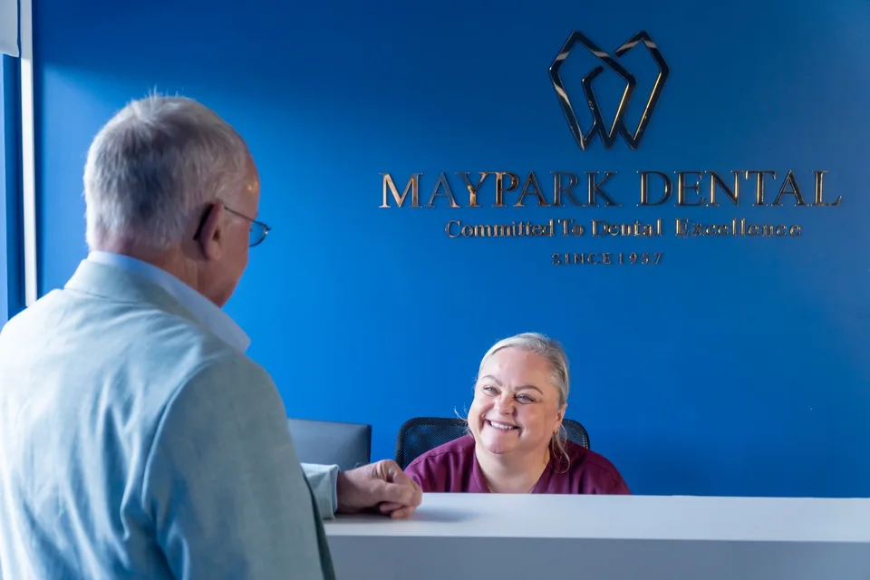 A patient being welcomed at the Maypark Dental reception desk